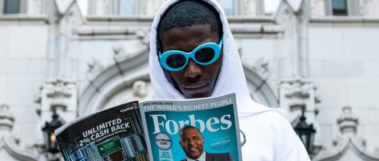 man in white thobe holding newspaper